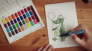 Eine Hand die mit Wasserfarben ein Krokodil malt