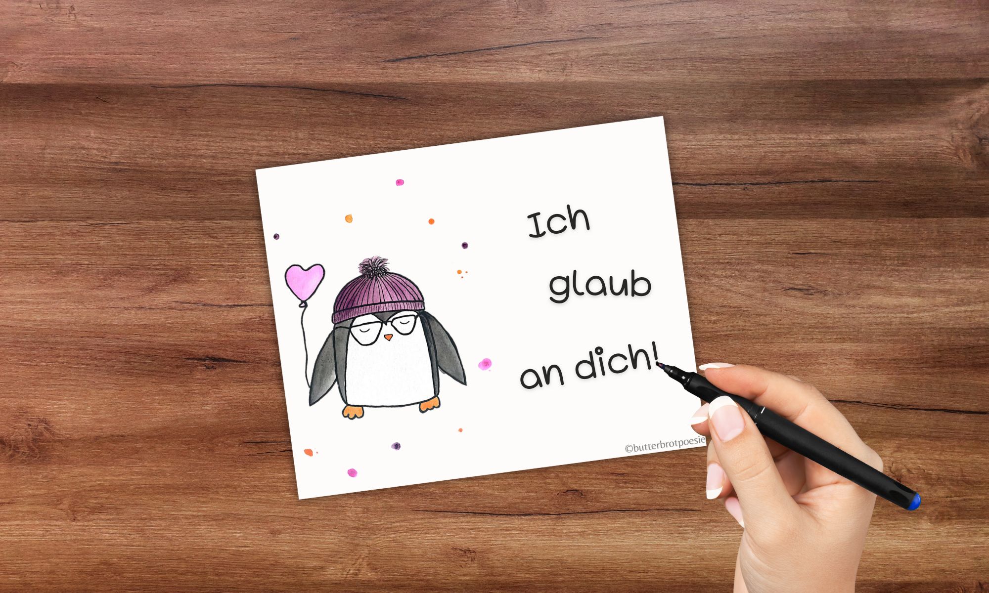 Brotboxkarte mit handgemaltem süßen Pinguin und einer Hand, die "Ich glaub an dich" schreibt